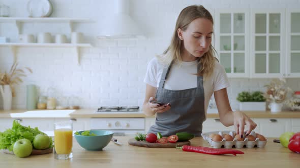 Woman Preparing Vegetables for Organic Salad Look at Smartphone.