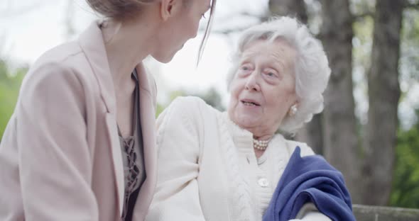 Grandmother Woman Kissing and Hugging Granddaughter at City Park