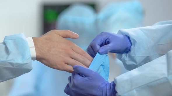 Nurse Helping Doctor to Put Medical Gloves Before Operation, Hospital Sterility