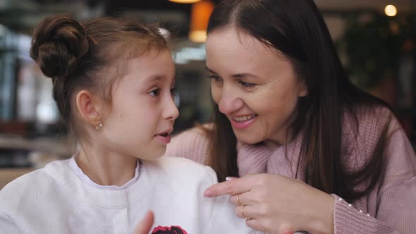 Attractive Caucasian Mother and Her Daughter Using Smartphone at the Cafe