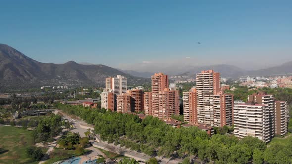 Aerial reveal of Luxury apartment buildings while a helicopter cross the skyline at Bicentenario Par