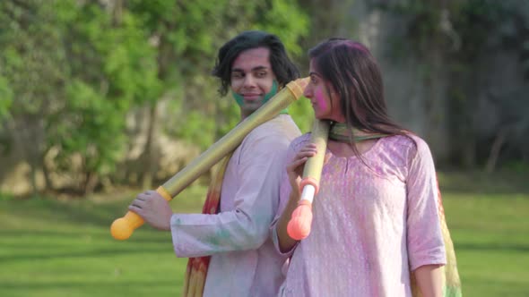 Indian couple posing for Holi with pichkari in hands