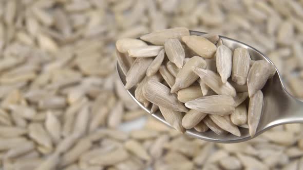 Raw uncooked peeled sunflower seeds fall from a spoon into a heap