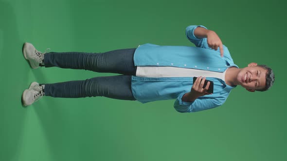 Full Body Of Asian Boy Use Mobile Phone And Pointing To Smart Phone In The Green Screen Studio