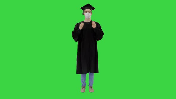 Young Man with Graduation Gown in Medical Mask on a Green Screen, Chroma Key