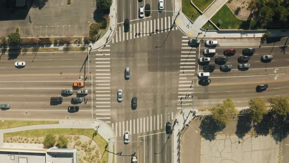 Top Down Aerial of Cars Driving By Cross Road Cityscape on Sunny Summer Day