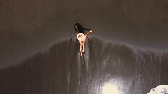 Unrecognizable Young Woman Sitting on Sandy Beach By Breaking Shoreline Waves, Aerial View.