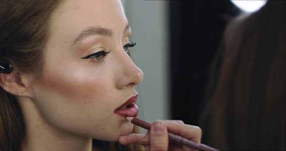 Closeup of Girl with Perfect Nude Makeup and Makeup Artist