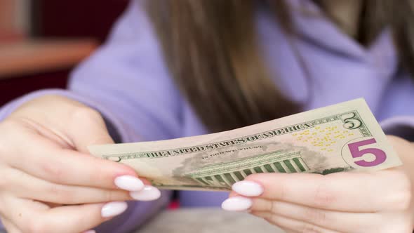 Close-up in women's hands 5 dollar bill. A woman holds in her hands examines a bill of 5 American do