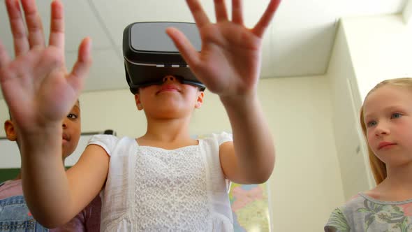 Mixed race schoolgirl using virtual reality headset in classroom at school 4k