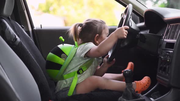 Baby Toddler Girl Sitting on Front Seat of Car with Steering Wheel. Back To School Ride