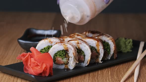Sprinkle Sushi with Sesame Seeds on a Wooden Table in Restaurant