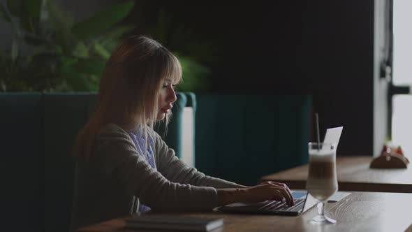 Young Asian Attractive Female Office Worker Sitting at a Coffee Shop at the Laptop Computer at the