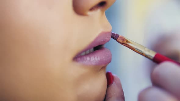 Closeup View of a Professional Makeup Artist Applying Lipstick on Model's Lips Working in Beauty