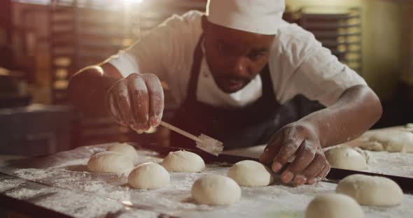 Animation of focused african american male baker preparing rolls