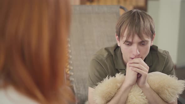 Depressed Young Man Sitting in the Office of Psychologist, Telling Her About His Problems