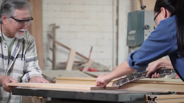 Carpenter man and woman use electric cutter to cut wood