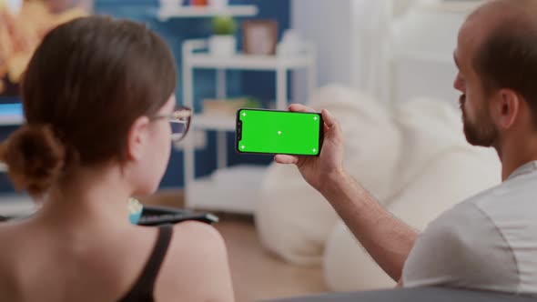 Closeup of Man Holding Smartphone with Green Screen Watching Online Video Content with Girlfriend