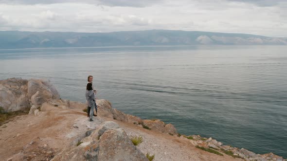 Travelers at the edge of the cliff Summer Baikal lake Olkhon island