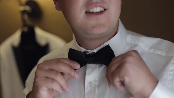 Groom Man Adjusts Bow Tie Preparing to Go to the Bride Businessman in White Shirt Wedding Day