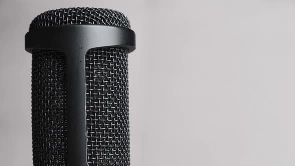 Studio Condenser Microphone Rotates on Gray Background with Place for Text