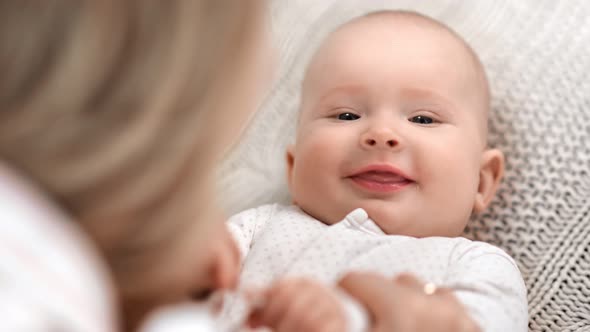 Closeup Face of Funny Cute Toddler Lying on Bed During Mother Playing