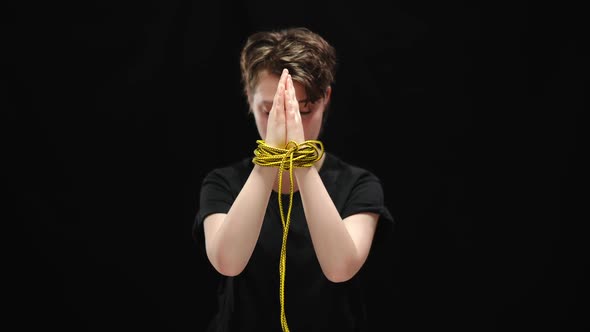 Clasped Female Hands Tied with Rope with Blurred Sad Woman at Background