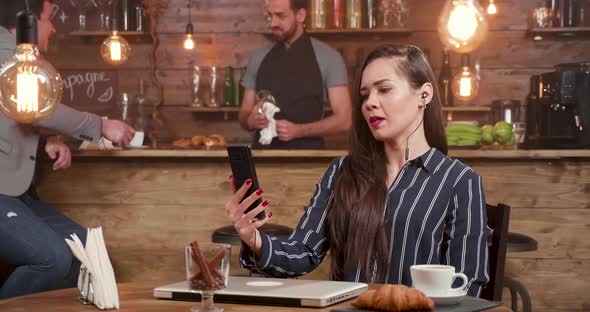 Young Businesswoman Engaged in a Video Call in a Coffee Shop