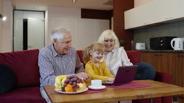 Senior Caucasian Couple with Child Girl Granddaughter Using a Laptop Computer, Watching Funny Videos