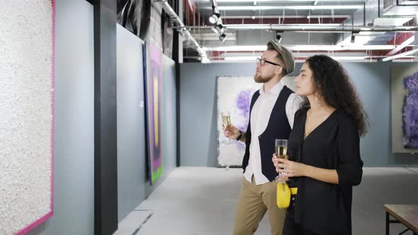 Man and Woman Is Drinking Champagne and Viewing Picture in Modern Art Gallery