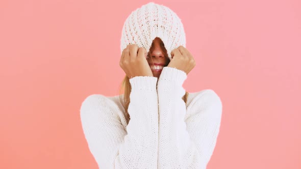 Young Lady in White Jumper is Laughing Pulling Knitted Hat Over Her Face Kissing you While Posing on