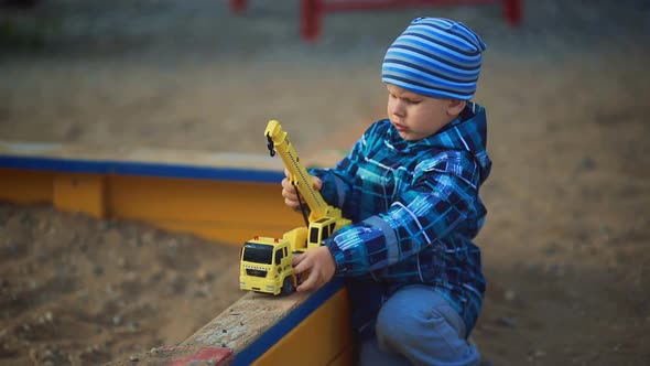 Child Playing in the Sandbox with Toy