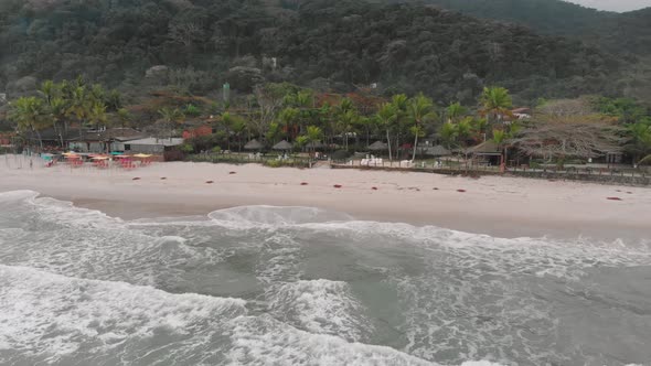 Drone footage of the beach above the sea, mountain in front of the sea, cloudy day, waves, landscape