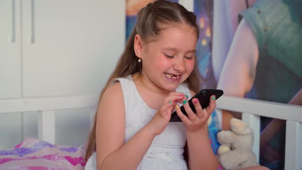 Little girl holding looking smartphone typing teeth smiling. Portrait young child relaxing online