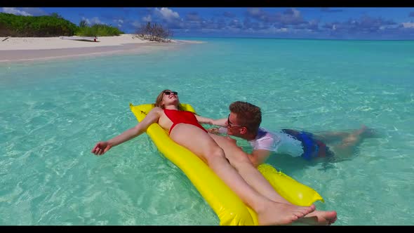 Guy and girl tanning on paradise resort beach vacation by clear water and white sandy background of 