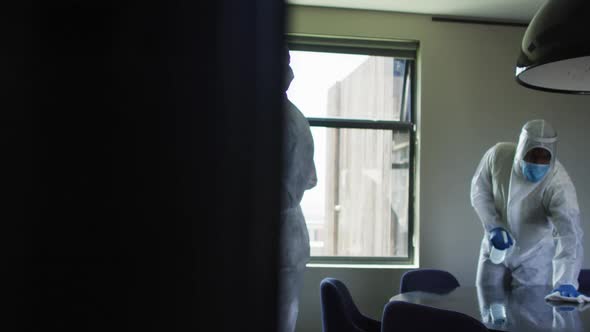 Team of health workers wearing protective clothes cleaning the office using disinfectant sprayer