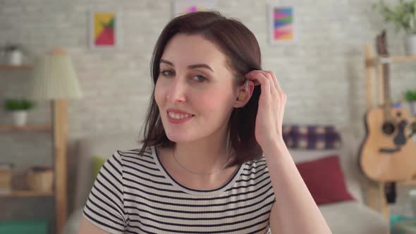 Hard of Hearing Young Woman with Hearing Aid in Her Ear Smiles