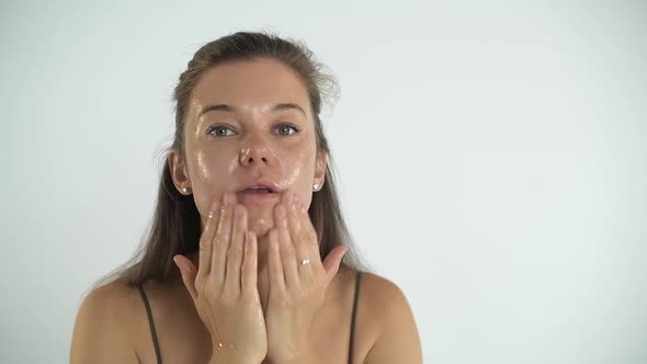 Young Pretty Girl Applies Cream to the Skin of the Face