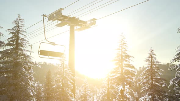 Empty Ski Lift. Chairlift Silhouette on High Mountain Over the Forest at Sunset