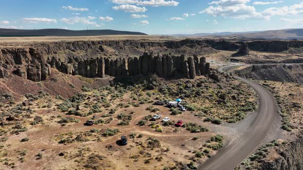 Orbiting drone shot of unique rock climbing feature with campers parked beneath.