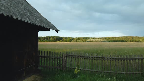 Flight Past An Old Barn, Over A Wooden Fence. Along A Grassy Meadow. At A Low Altitude