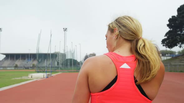 Rear view of Caucasian female athlete practicing shot put throw at sports venue 4k