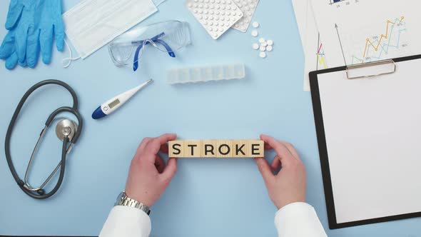 Word stroke of wooden cubes is put by the hands of the doctor on table with medical belongings.