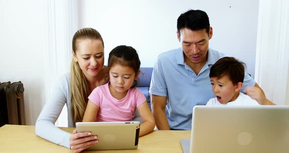 Happy family using digital tablet and laptop in living room