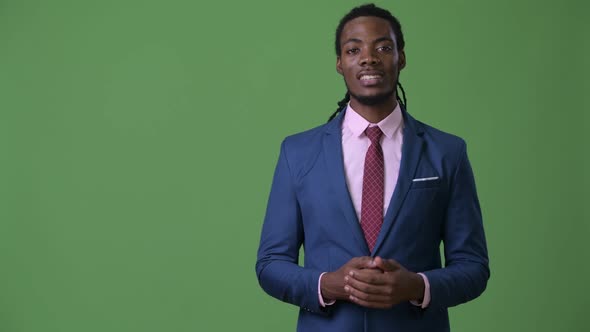 Young Handsome African Businessman with Dreadlocks Against Green Background