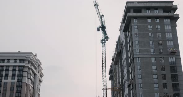 Crane working on construction site under grey cloudy sky on rainy day