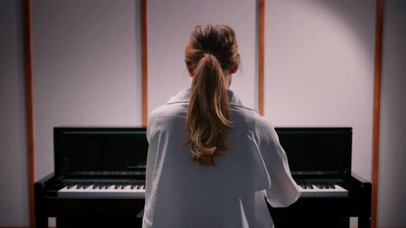 Woman sensually playing the piano view from the back