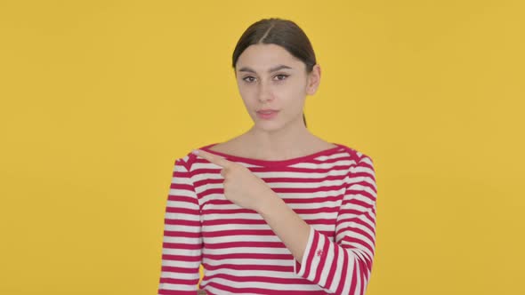 Spanish Woman Pointing Towards Product on Yellow Background