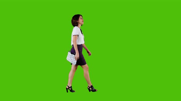 Stylish Happy Businesswoman Walking and Smiling Over a Green Screen in A Full Side Shot