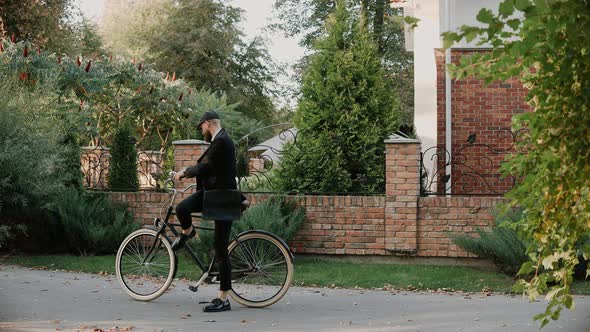 Young Businessman Gets Off the Bike and Answers the Phone in Green Suburbs